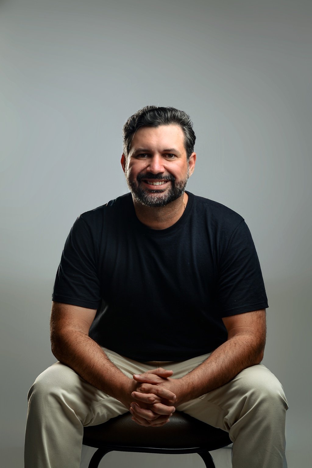 Francis Eduan sentado, sorrindo, em ambiente profissional